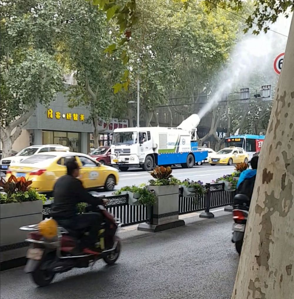 A street cleaning truck spraying water up behind it