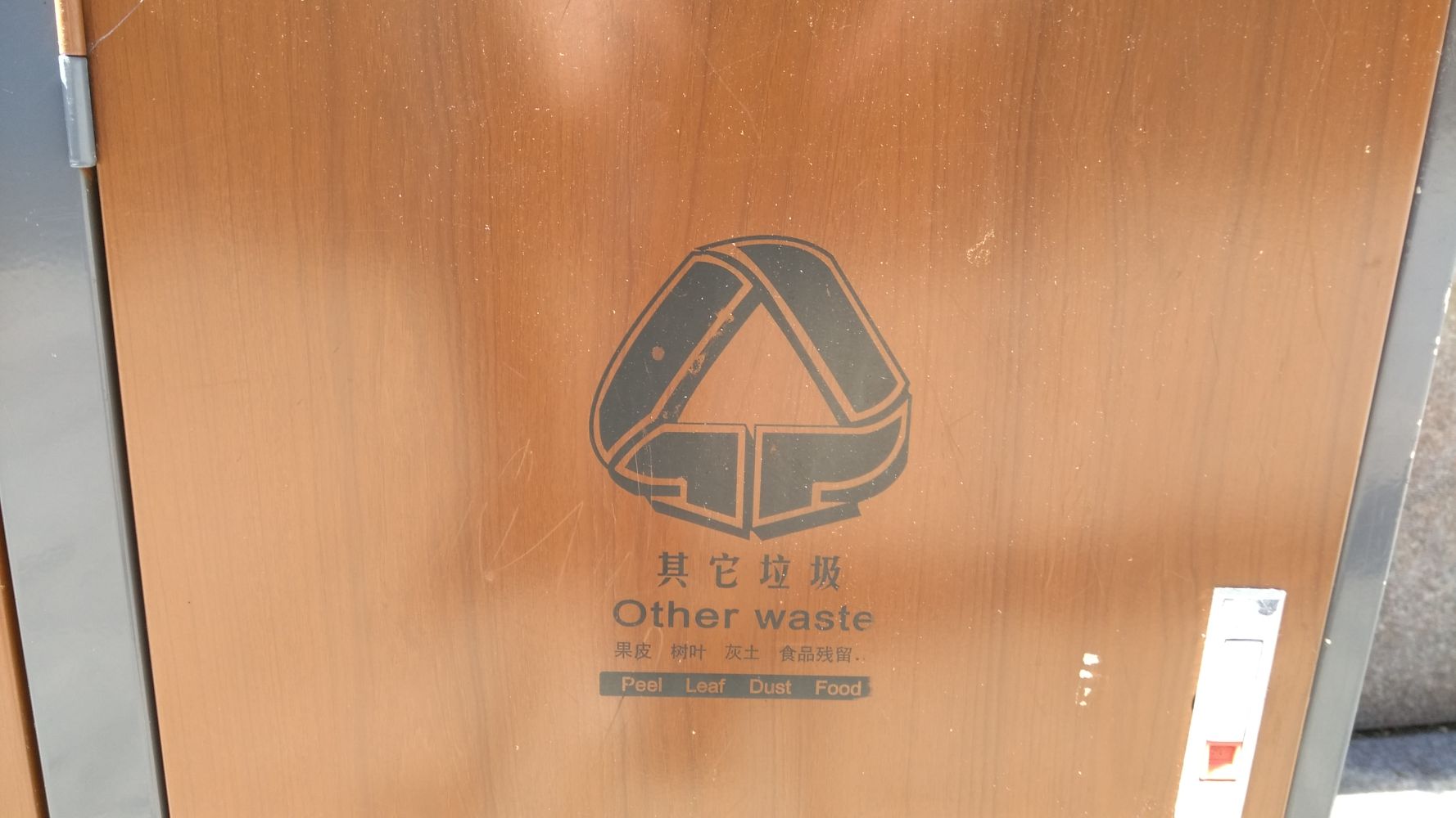 A bin that says other waste with an adapted recycling icon that points down into the ground