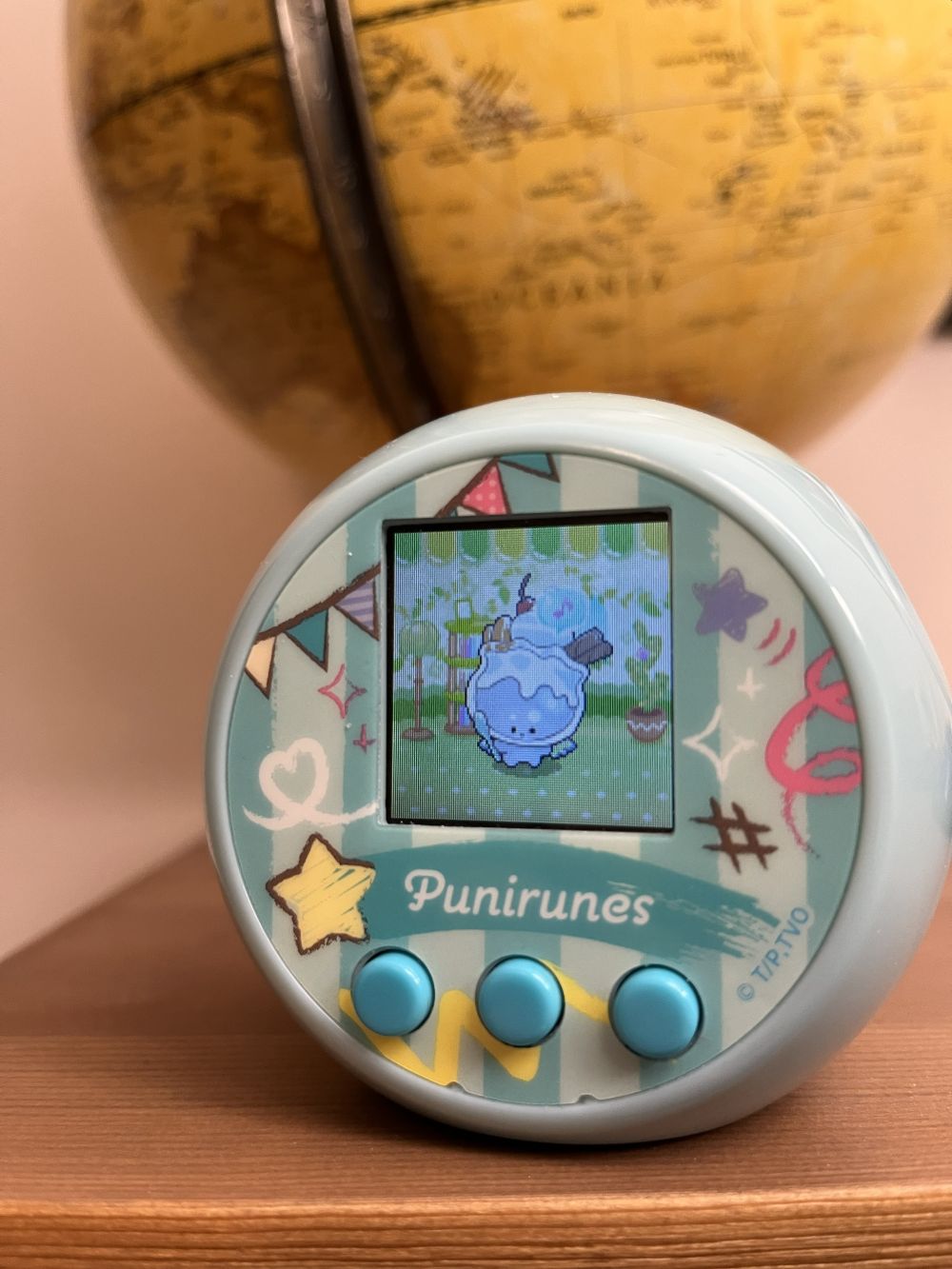 The Paferun character is displayed on a blue Punirunes device, sat on a shelf next to a sepia globe